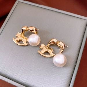 Detailed macro view of vintage gold rocking horse earrings with elegant white pearls