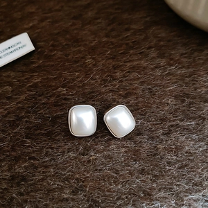 Vue macro de boucles d'oreilles carrées en perles et argent sur une fourrure noire