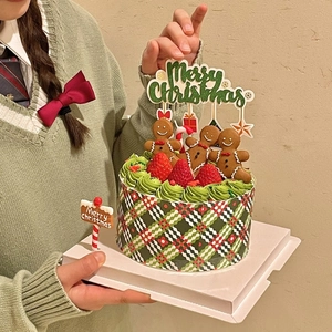 Close-up of a Christmas cake with gingerbread men and a glittery Merry Christmas topper