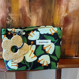 Canvas makeup bag with tropical leaf pattern, floral pendant and secure zipper closure