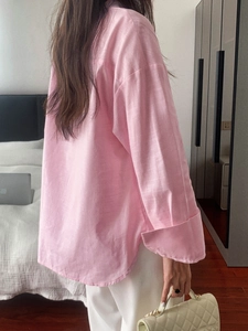 Pink loose-fit long sleeve shirt with folded cuffs, back view on female model in bedroom