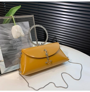 Detail of yellow leather evening bag featuring a rhinestone circular handle and chain