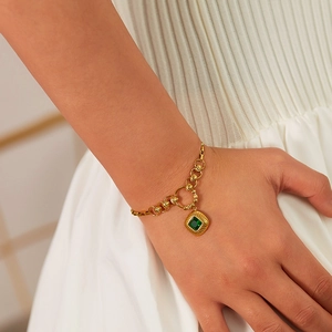 Detailed shot of a vintage gold chain bracelet featuring a square emerald zircon charm