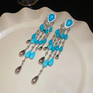 Detailed macro of silver flower earrings with turquoise beads and cascading long tassels
