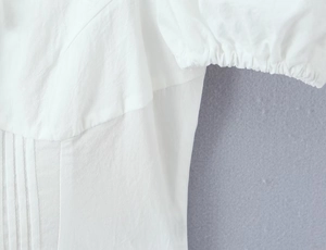 Détail de gilet en dentelle blanche avec texture plissée et finitions élastiques