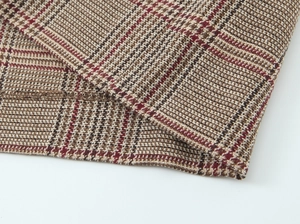 Macro detail of houndstooth fabric showing brown and red weave and fine stitching