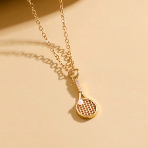 Macro shot of gold tennis racket pendant necklace with a pearl and sparkling zircons