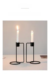 Detail of two black minimalist geometric iron candle holders with white spiral candles