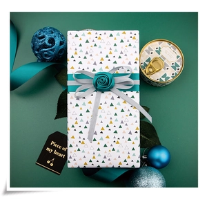 Elegant white gift box with geometric patterns and layered green satin ribbon bow