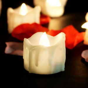 Detailed view of LED electronic candles with dripping wax design on a romantic red petal setting