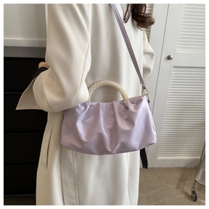 Detail of lavender ruched handbag with pearl handle on model in white coat