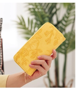 Detail of yellow faux leather long wallet featuring embossed floral petal patterns