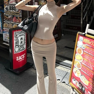 Close-up of beige knit sleeveless halter top and flared trousers on a city street