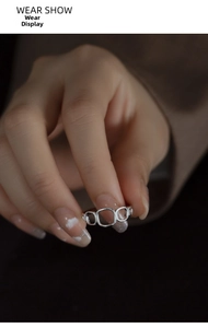 Close-up of a silver geometric hollow ring on hand featuring rounded rectangular links
