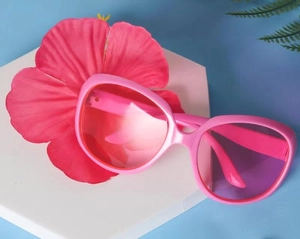 Rosa Party-Sonnenbrille im Ananas-Design auf weißem Ständer mit tropischen Blumen