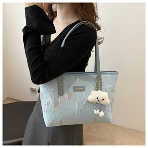 Close-up of light blue canvas tote bag texture with cute white plush cloud charm accessory