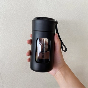 Detail of matte black water bottle featuring vertical transparent window and carry strap