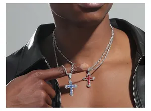 Detail of hip hop iced out cross pendant with blue and red stones on a silver rope chain