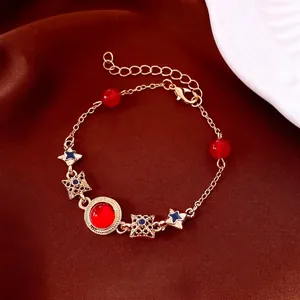 Vintage style gold bracelet with red beads and black star charms on red satin