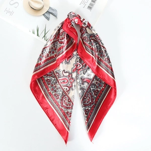 Close-up of red and beige paisley square scarf on white background with fashion props