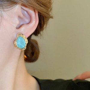 Detail of vintage gold lava earrings with blue drop stones worn by a model