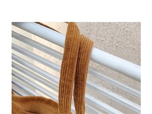 Detailed close-up of brown corduroy fabric and shoulder strap on a retro tote bag
