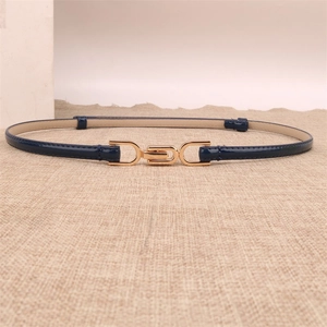Detail view of a slim navy blue patent leather belt with a minimalist gold metal buckle