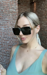 Detail of square oversized sunglasses with gold filigree temples and dark lenses