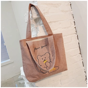 Detail of pink corduroy tote bag with black bear embroidery and soft ribbed texture
