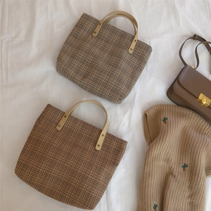 Flat lay of vintage plaid canvas tote bags with brown leather handles and knit sweater