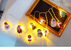 Close-up of LED Christmas string lights with Santa and snowman pendants in warm yellow glow