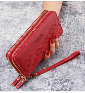 Detail of red embossed leather long wallet featuring double gold zippers and wrist strap