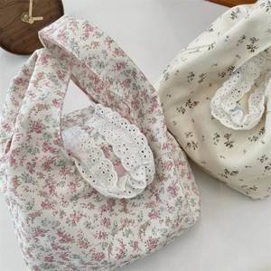 Close-up of floral canvas wristlet bags featuring intricate white lace trim and patterns