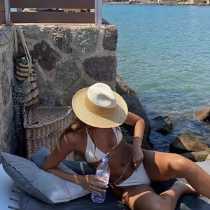 Women's wide brim raffia straw hat paired with white bikini for stylish beach sun protection