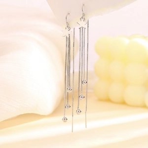 Macro shot of silver star tassels earrings with dangling metallic beads and long chains