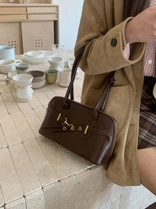 Detail of dark brown leather bowling bag featuring double straps and metal hardware