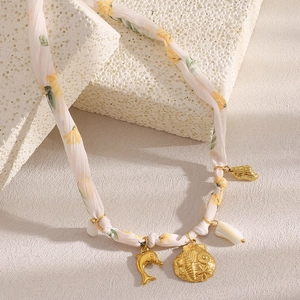 Detail of seashell and dolphin charms on a floral fabric strap 18K gold plated necklace