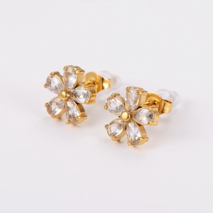 Detail of gold floral stud earrings with sparkling clear crystals on white background