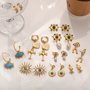 Flat lay of evil eye and cross earrings with turquoise and pearls on white surface