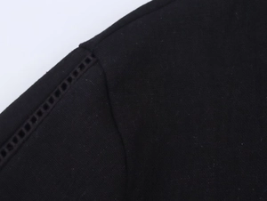 Close-up of black linen shirt showing shoulder hollow-out stitching and detailed fabric texture