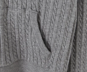 Detailed close-up of grey cable knit texture and ribbed side pocket on casual cardigan