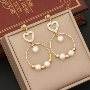 Golden heart earrings with pearls and crystals displayed on a soft jewelry box background