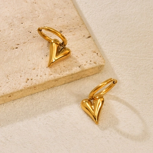 Minimalist gold heart-shaped dangle earrings on textured stone base with natural lighting