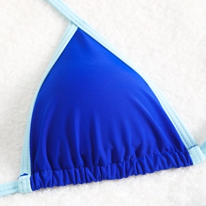 Blue two-tone bikini top with triangle cups and contrast trim on white faux fur background