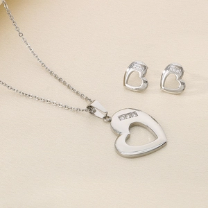 Detailed view of silver stainless steel heart necklace and stud earrings set with rhinestones