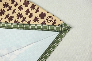 Dettaglio macro del tessuto beige con stampa a quadrifoglio e bordo a scacchi verdi