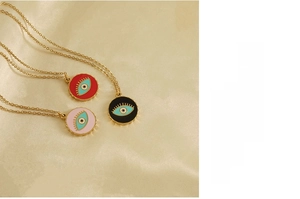 Detailed close-up of evil eye necklaces in red, pink, and black on a gold silk background