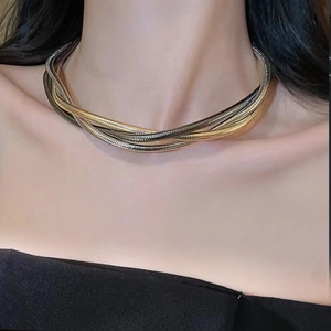 Detail view of multi-layer snake bone necklace in mixed gold and silver tones on a model