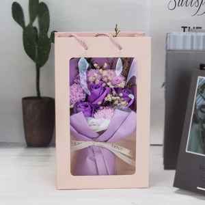 Close-up of purple soap flower bouquet with roses and carnations in a pink gift bag