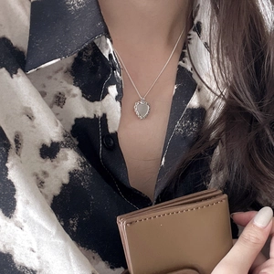 Close-up of a 925 sterling silver heart necklace with embossed texture on a model
